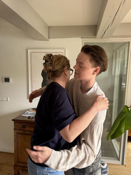 This photo captures two individuals in a warm embrace within a cozy home interior, likely at Staalkade, Centrum, Amsterdam